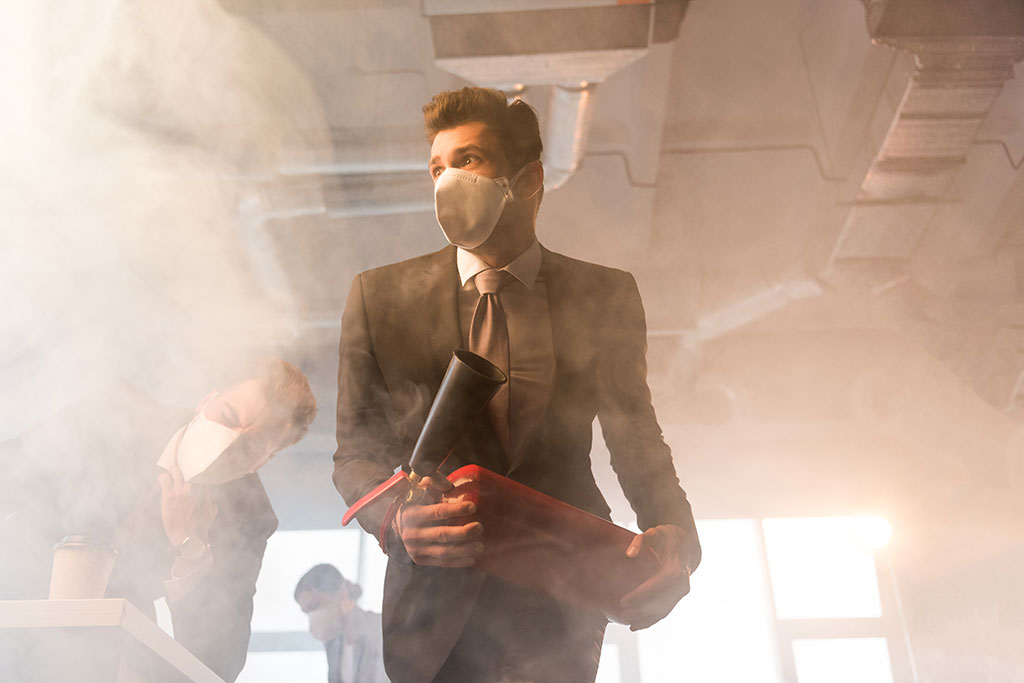 Frightened businessman in mask holding extinguisher