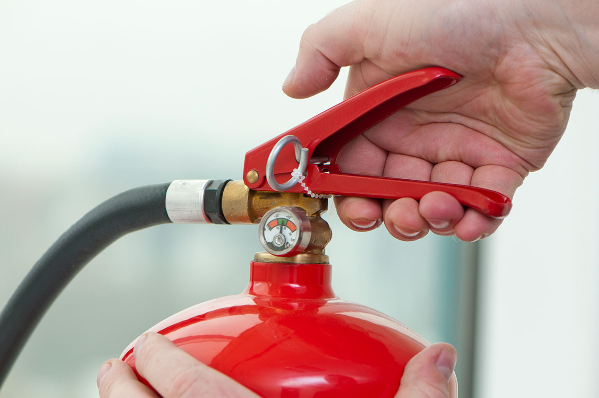 Hand presses the trigger fire extinguisher
